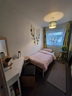 a bedroom with a bed and a desk and a window at The Green Box in Great Clacton