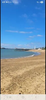 a sandy beach with a pier in the water at The Green Box in Great Clacton