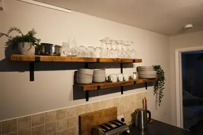 a kitchen with wooden shelves with glasses on the wall at The Granary Cottages