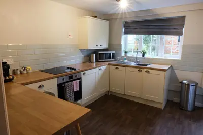 a kitchen with white cabinets and a sink and a counter at The Granary Cottages
