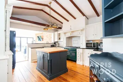 a kitchen with white cabinets and a blue island at Harvest Close, Marks Tey in Marks Tey