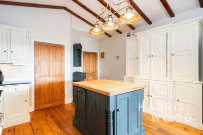 a kitchen with white cabinets and a blue island at Harvest Close, Marks Tey in Marks Tey