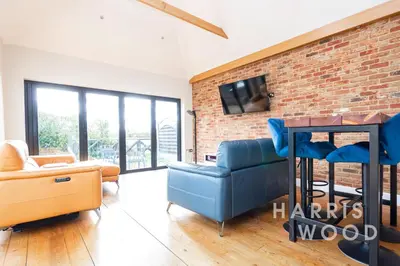 a living room with a blue couch and a brick wall at Harvest Close, Marks Tey in Marks Tey
