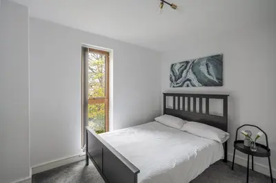 a white bedroom with a bed and a window at Modern Apartment in Chelmsford City, Free WiFi & Free Parking - Dukes Apartment by Stays Accommodation - Long Stays Welcome in Chelmsford