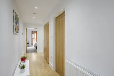 a hallway with white walls and a wooden door at Modern Apartment in Chelmsford City, Free WiFi & Free Parking - Dukes Apartment by Stays Accommodation - Long Stays Welcome in Chelmsford