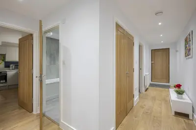 an empty hallway with wooden doors and a kitchen at Modern Apartment in Chelmsford City, Free WiFi & Free Parking - Dukes Apartment by Stays Accommodation - Long Stays Welcome in Chelmsford