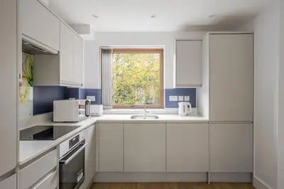 a kitchen with white cabinets and a window at Modern Apartment in Chelmsford City, Free WiFi & Free Parking - Dukes Apartment by Stays Accommodation - Long Stays Welcome in Chelmsford