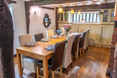 a dining room with a long wooden table and chairs at 3 Bed Country House with Pool and Sauna in Tibenham