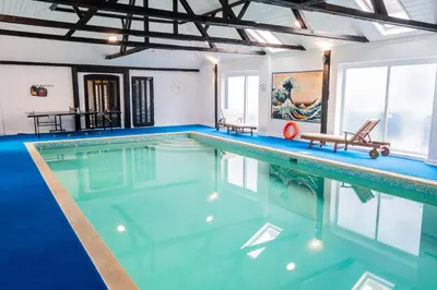 a swimming pool with blue water in a building at 3 Bed Country House with Pool and Sauna in Tibenham