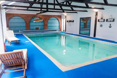 a large swimming pool in a house with blue flooring at 3 Bed Country House with Pool and Sauna in Tibenham