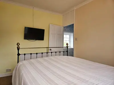 a bedroom with a bed with a tv on the wall at B&B Rooms in terraced house in Sudbury centre in Sudbury