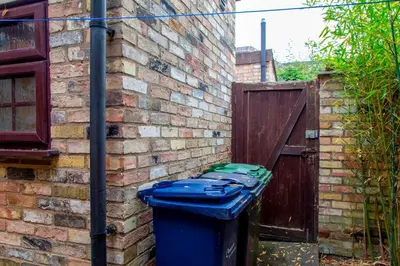 a blue trash can sitting next to a brick wall at Stylish Victorian Terrace in Central Cambridge Pass the Keys in Cambridge