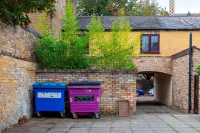 two trash cans are parked next to a brick building at Stylish Victorian Terrace in Central Cambridge Pass the Keys in Cambridge