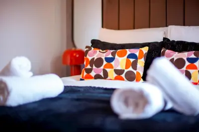 a bed with colorful pillows on top of it at Stylish Victorian Terrace in Central Cambridge Pass the Keys in Cambridge