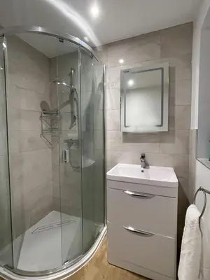 a bathroom with a shower and a sink and a mirror at Luxury 1 bed new build house near Science & Business parks in Cambridge