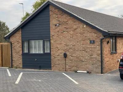 a brick building with a black roof and a parking lot at Luxury 1 bed new build house near Science & Business parks in Cambridge