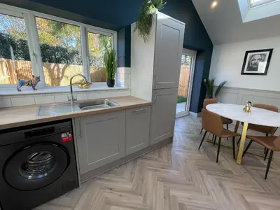 a kitchen with a washing machine and a table at Luxury 2 bed new-build house near Science & Business parks in Cambridge