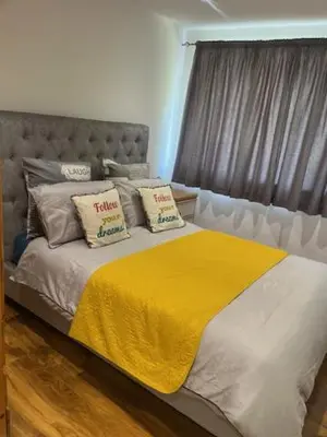 a bedroom with a bed with a yellow blanket on it at Maxismile Haven in Southend-on-Sea