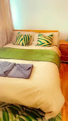 a bed with green and yellow sheets and pillows on it at Maxismile Haven in Southend-on-Sea