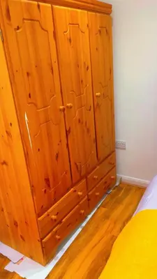 a wooden cabinet in a bedroom with a bed at Maxismile Haven in Southend-on-Sea