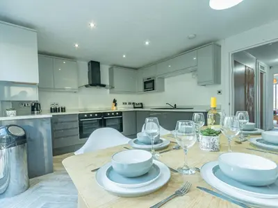 a kitchen with a wooden table with plates and wine glasses at Pass the Keys Large 4 Bedroom Home Stunning views Contractor in Basildon