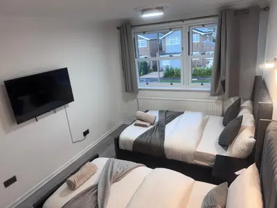 a room with two beds and a flat screen tv at Ama comfort Stay in Hythe