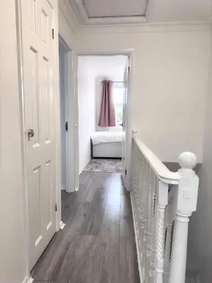 a white hallway with a staircase and a bedroom at Ama comfort Stay in Hythe