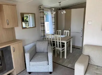 a kitchen and dining room with a table and chairs at Caravan With Front Decking At Coopers Beach Holiday Park Ref 49080Pa in East Mersea