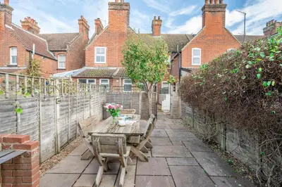 a patio with a wooden table and a fence at Number 22, Leiston Road, Aldeburgh in Aldeburgh