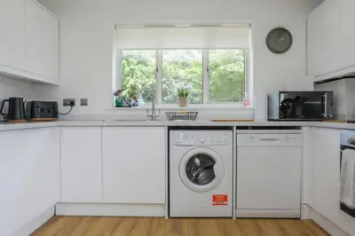 a white kitchen with a washer and dryer at Iris Group Stay 8-BR Free Parking in Wenhaston