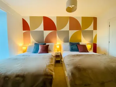 two beds in a room with a colorful wall at Autumn House Cambridge free parking in Trumpington