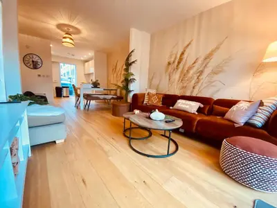 a living room with a brown couch and a table at Autumn House Cambridge free parking in Trumpington