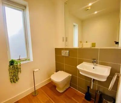 a bathroom with a toilet and a sink and a mirror at Autumn House Cambridge free parking in Trumpington