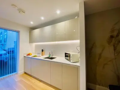 a kitchen with white cabinets and a microwave at Autumn House Cambridge free parking in Trumpington