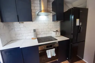 a kitchen with black cabinets and a black refrigerator at Beautiful 2 Bed Home with Spacious Garden in Shephall