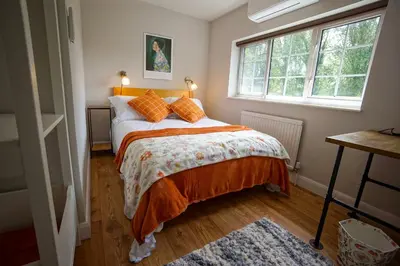 a bedroom with a bed with orange pillows and a window at Beautiful 2 Bed Home with Spacious Garden in Shephall