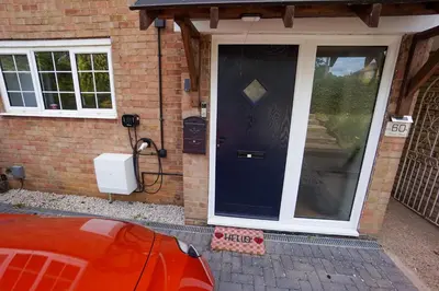 a front door of a house with a red car in front at Beautiful 2 Bed Home with Spacious Garden in Shephall