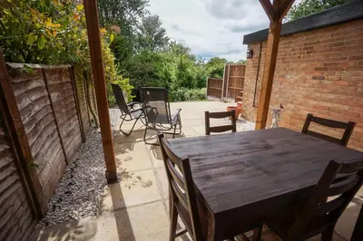 a wooden table and chairs on a patio at Beautiful 2 Bed Home with Spacious Garden in Shephall