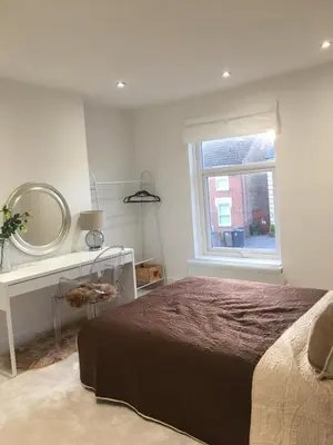 a bedroom with a bed and a mirror and a window at Spacious 3-bedroom Ipswich House with Parking in Ipswich