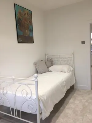 a white bed in a bedroom with a painting on the wall at Spacious 3-bedroom Ipswich House with Parking in Ipswich