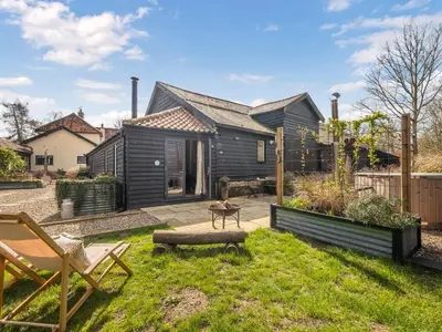 a backyard with a black house and a lawn with a chair at The Old Press - Uk50806 in Halesworth