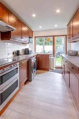 a large kitchen with wooden cabinets and stainless steel appliances at Pass the Keys 3-Bedroom Home in Chelmsford Sleeps 7 in Chelmsford