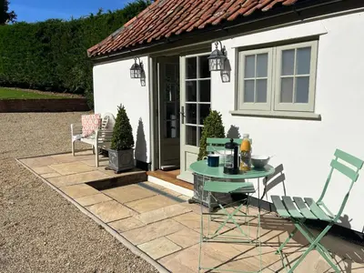 a patio with a table and chairs in front of a house at Luxury Designer Boutique Annexe - Walk to Award Winning Pub in Sibton
