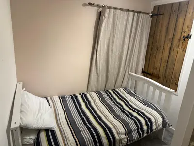 a bedroom with a bed with a curtain and a window at Cosy two bedroom house in eye Suffolk with parking near A140 in Eye