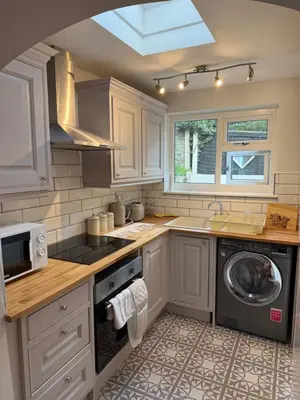 a kitchen with white cabinets and a washer and dryer at Cosy two bedroom house in eye Suffolk with parking near A140 in Eye
