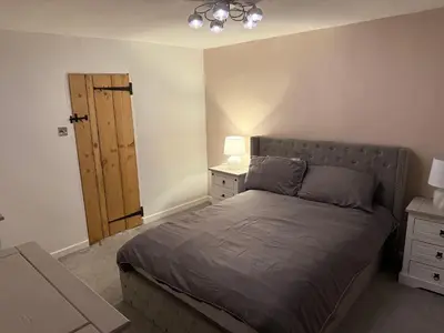 a bedroom with a bed and a wooden door at Cosy two bedroom house in eye Suffolk with parking near A140 in Eye