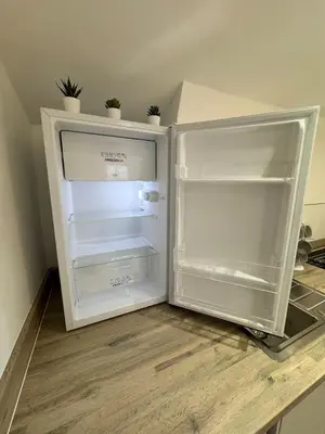 an empty refrigerator sitting on top of a counter at Cinema room apartment 1 in Basildon