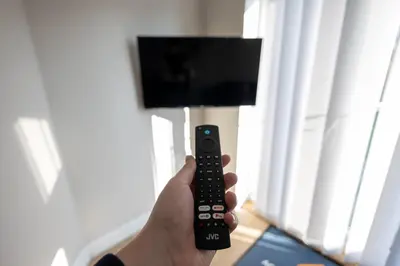 a person holding a remote control in front of a television at The Nook - Sizewell - Contractor Accommodation in Aldringham