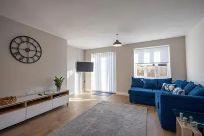 a living room with a blue couch and a clock at The Nook - Sizewell - Contractor Accommodation in Aldringham