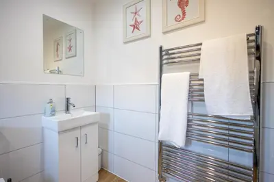 a white bathroom with a sink and a mirror at The Nook - Sizewell - Contractor Accommodation in Aldringham
